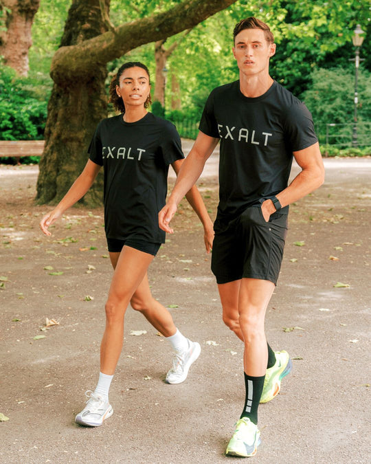 Shot of Male and Female walking in the park whilst wearing Black EXALT x Lululemon Fundamental Tee.