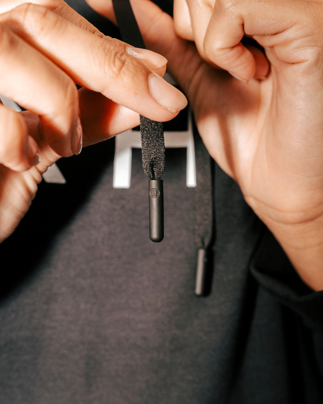 Close up of lululemon logo on hoodie drawstrings.