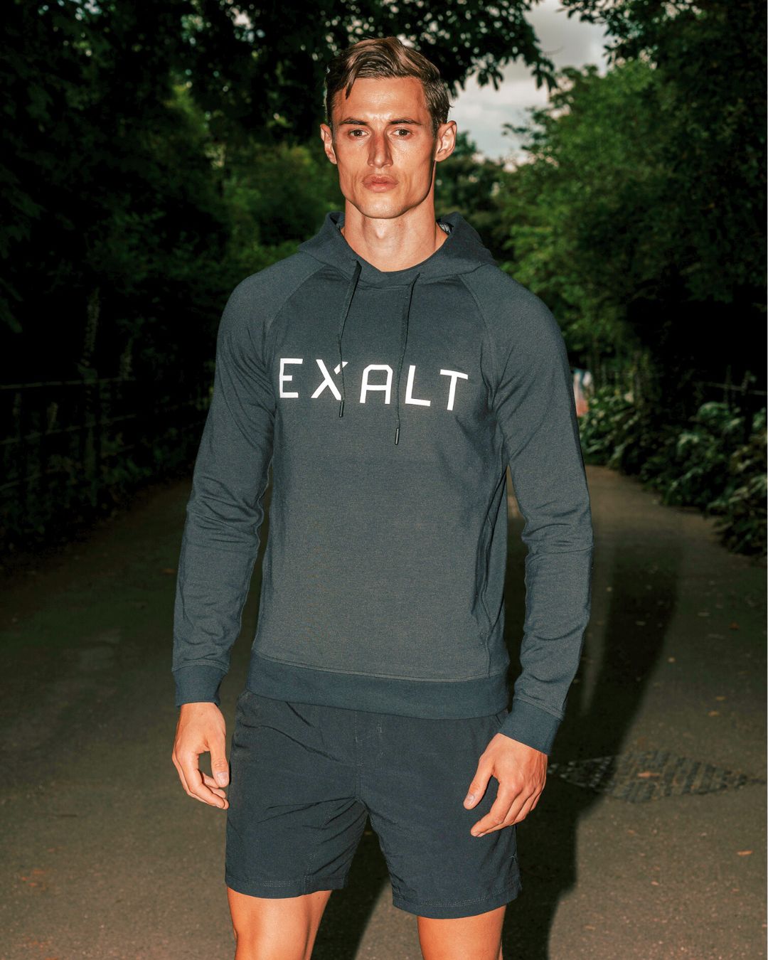 Man wearing Black EXALT x Lululemon City Sweat Hoodie in a park with trees in background